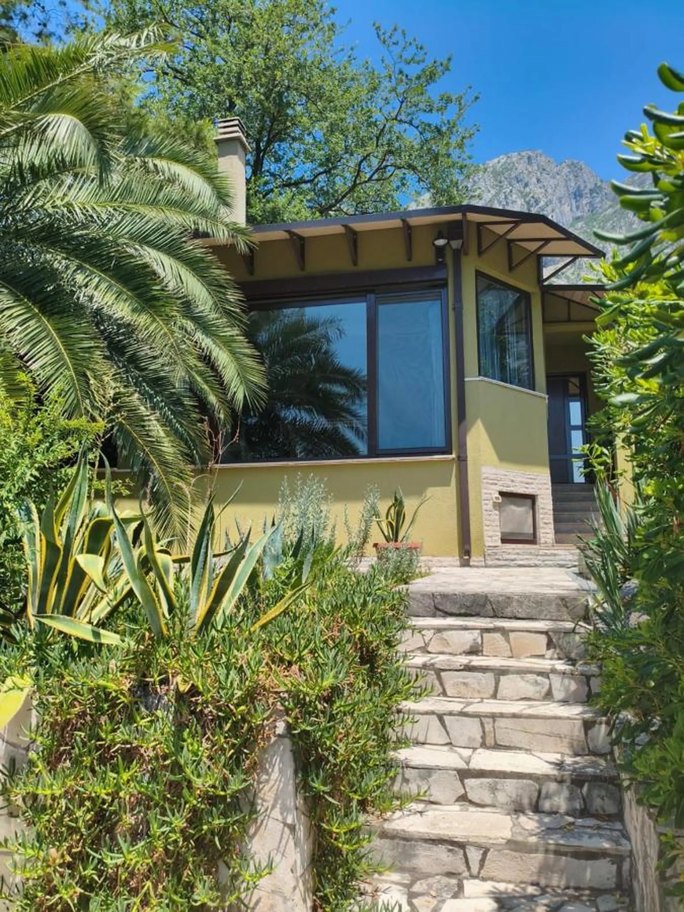 Photo of the house, green garden, and view over the Bay of Kotor